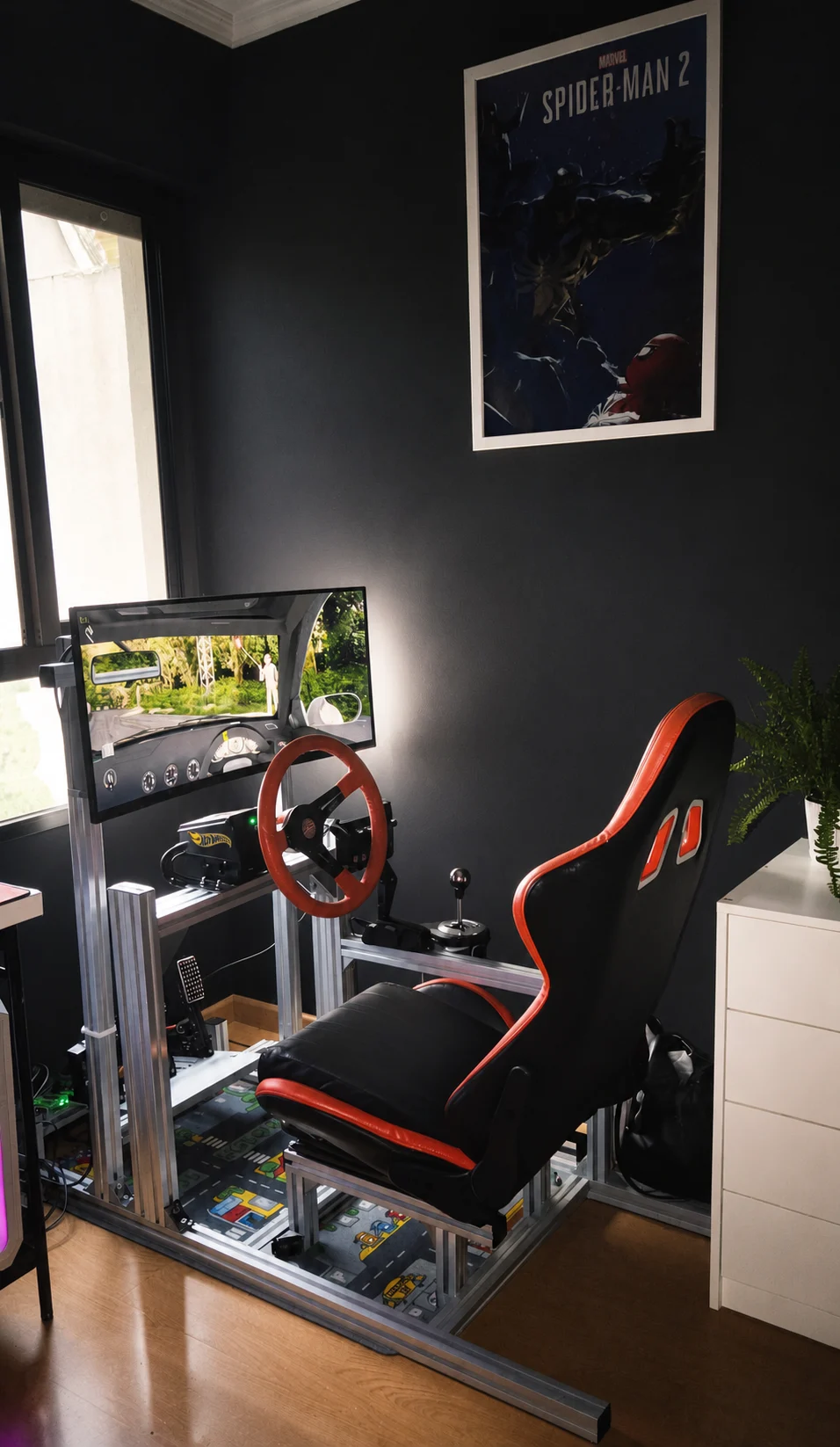 Cockpit de aluminio instalado por un cliente, con asiento negro y naranja, volante y shifter en una habitación oscura.